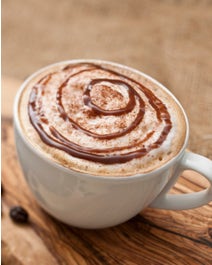 Coffee in a mug with chocolate drizzle and dusted with cinnamon.