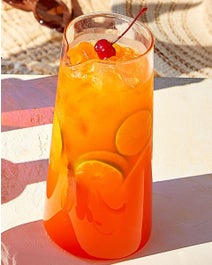 Pineapple and orange juice with fruit on a table outside.