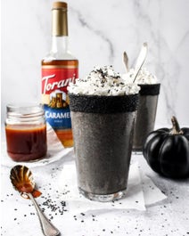 Sesame caramel frappe with black pumpkin on table.