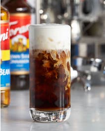 Cold brew in a glass with cake batter flavor foam.
