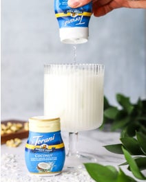 Coconut Jasmine Tea in a glass with coconut drink enhancer being squeezed on top.