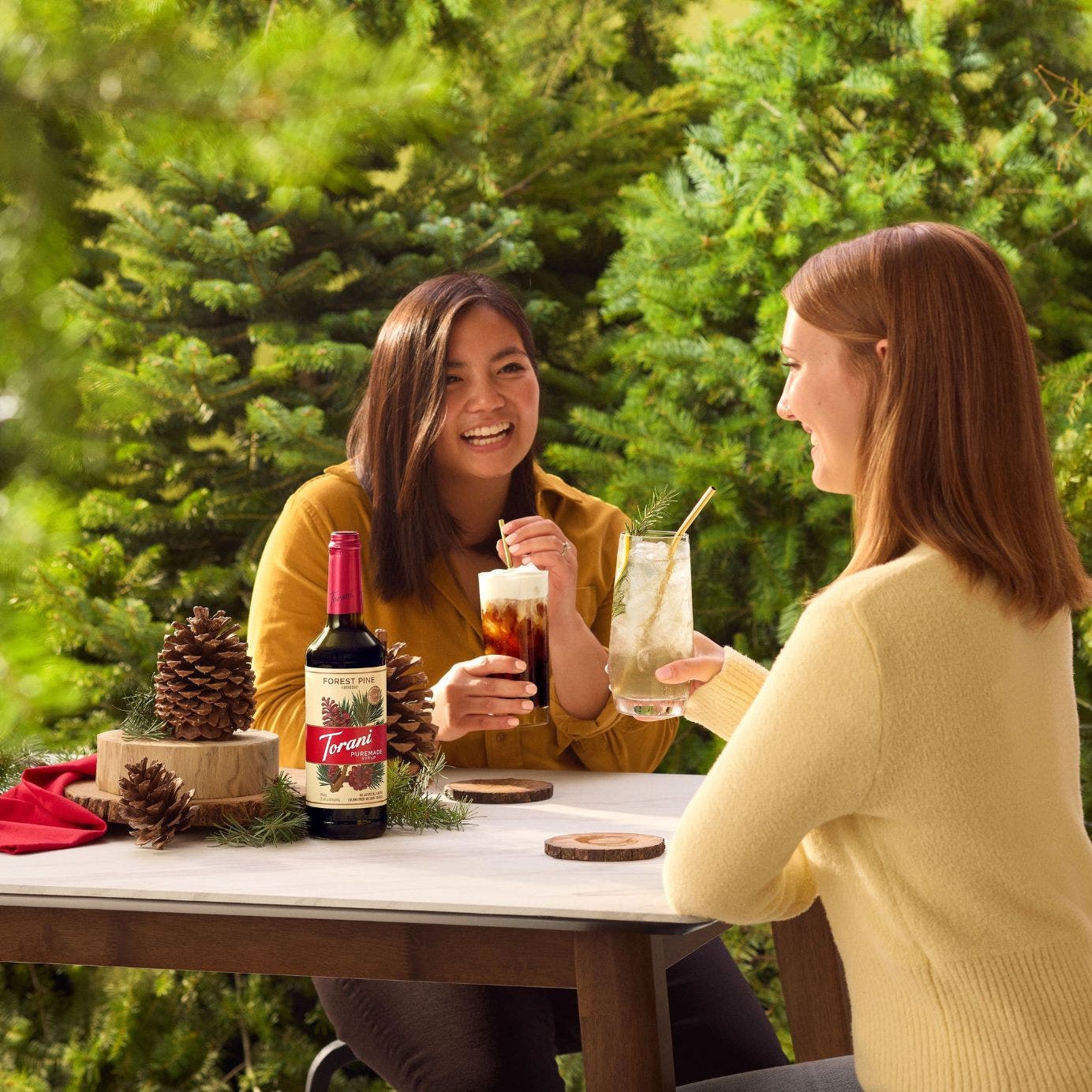 Lifestyle image of Torani Puremade Forest Pine Syrup being enjoyed by two people 