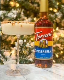 Gingerbread mocktail in a glass in front of Christmas tree.