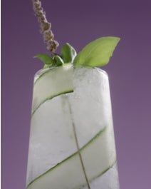 Sugar Free Lavender Sparkling Mocktail in a glass with lavender sprig, mint, and cucumber peel.